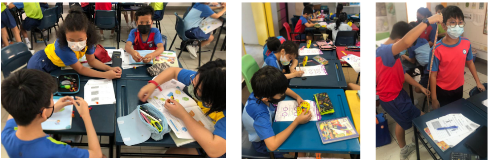 Young students wearing face masks work on papers at blue desks in a classroom, with one boy holding a ruler.